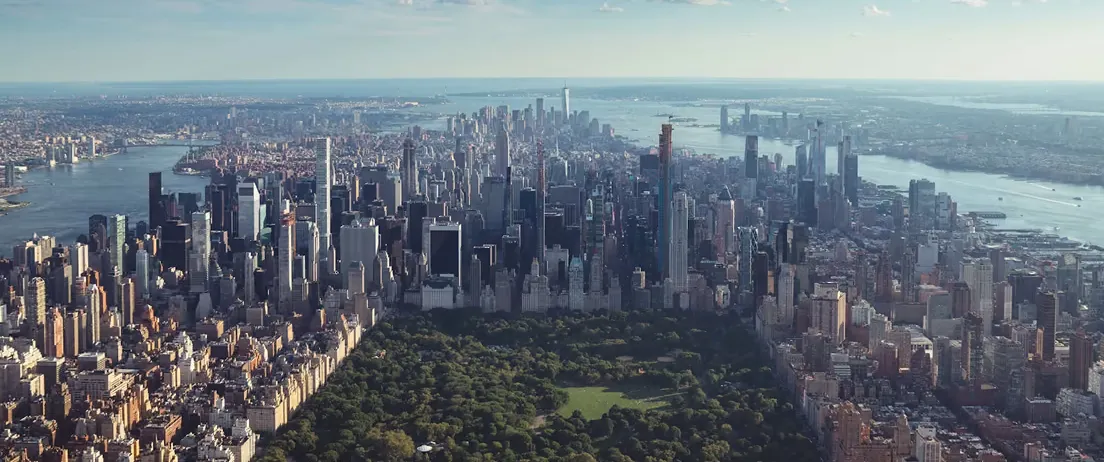Panoramablick auf die Skyline von New York City mit dem One World Trade Center unter einem teils bewölkten Himmel.
